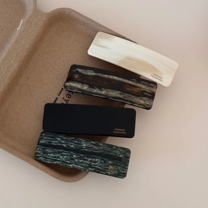 Rectangle acetate hair clips set in marble and tortoise shell patterns with gold label