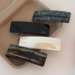 Detail of assorted marble and solid rectangle hair clips in an eco-friendly tray
