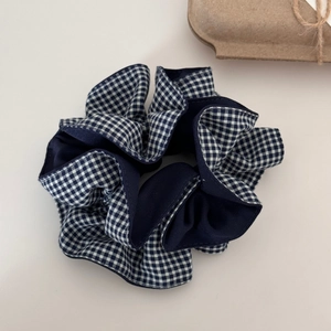 Gros plan d'un grand chouchou à carreaux bleu marine et blanc en tissu de coton doux