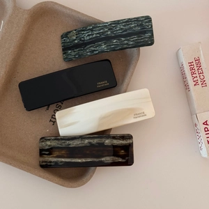 Detailed close-up of acetate hair clips with gold handmade logos in various marble colors