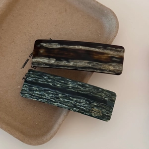 Detail of rectangular acetate hair clips with amber and green marble textures
