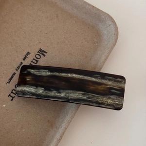 Detailed macro view of rectangular acetate hair clip with tortoiseshell marble texture