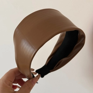 Detail view of the brown wide-brimmed PU leather headband with soft matte texture