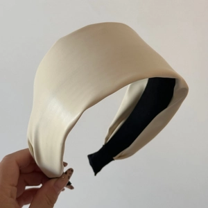 Detail of soft cream PU leather headband with fine texture and black fabric lining