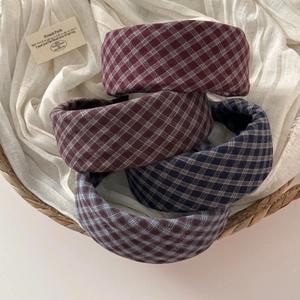 Close-up of four plaid padded headbands in red, brown, and navy in a woven basket