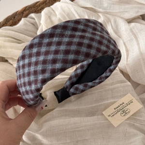 Close-up of a wide padded headband featuring a vintage blue and brown checkered pattern
