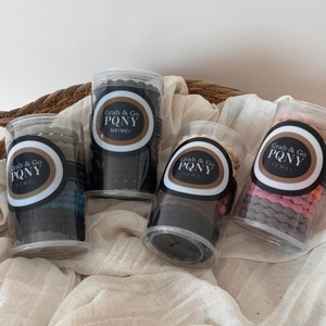 Vue détaillée d'élastiques à cheveux variés en pots transparents sur du linge
