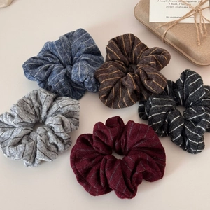 Detailed close-up of five striped knit scrunchies in assorted warm autumn colors