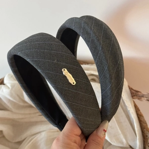 Macro detail of grey twill sponge headband with handmade gold metal logo plate