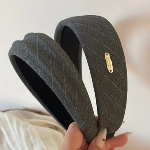 Detail of grey striped padded headband with handmade gold metal logo and non-slip lining