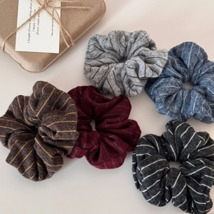 Detailed view of five striped knitted scrunchies in autumn colors for women's hair