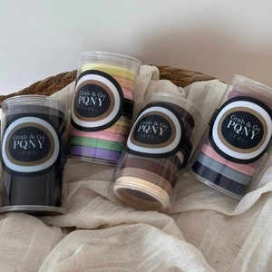 Lot de quatre cylindres avec des élastiques à cheveux colorés dans un panier tressé