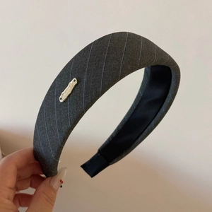 Detailed view of the gray pinstripe fabric and silver metal logo on a padded headband