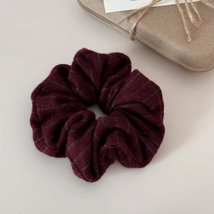 Close-up of a burgundy striped knitted scrunchie with soft fabric texture and ruffles
