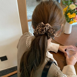 Detail of leopard print scrunchie on a low ponytail with coffee shop background