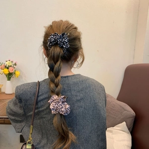 Detail of leopard print scrunchies set in pink and black on a braided hairstyle