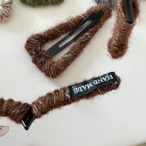 Close-up of brown knit wool-wrapped triangular BB hair clip with Hand Made label details
