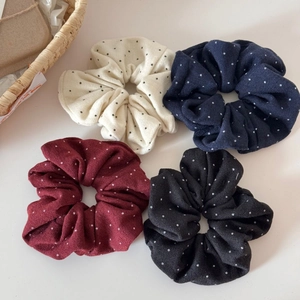 Dettaglio di quattro elastici per capelli a pois in crema, blu, rosso e nero elegante