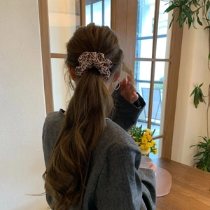 Close-up of leopard print hair scrunchie tied on a low ponytail with fabric texture detail