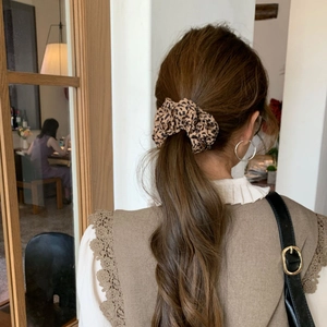 Close-up of a leopard print scrunchie styled on a low ponytail for a vintage look