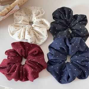 Dettaglio di quattro elastici per capelli a pois in crema nero rosso e blu navy