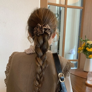 Close-up of leopard print scrunchie with Hand Made label on a braided hairstyle