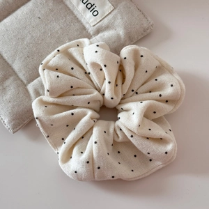 Dettaglio dell'elastico scrunchie oversize crema con pois neri e trama in maglia