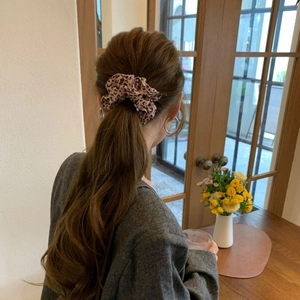 Detailed view of a leopard print scrunchie styled in a low ponytail for an elegant look