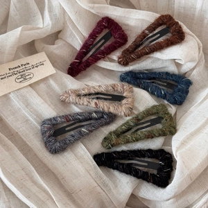 Set of six triangular hair clips wrapped in colorful wool yarn on beige linen
