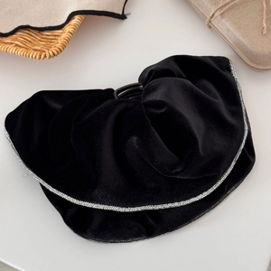 Detail of black velvet hair claw clip with silver rhinestone trim on a neutral background
