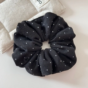 Primo piano di un grande elastico scrunchie nero a pois bianchi in maglia morbida