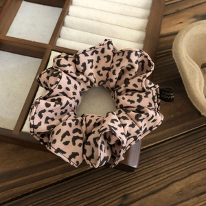 Detail of leopard print scrunchie showing fine fabric texture and woven brand label