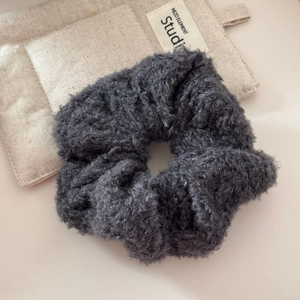 Détail du chouchou en peluche grise avec texture douce et duveteuse et bande élastique