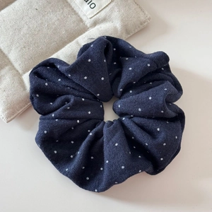 Dettaglio dell'elastico per capelli blu a pois con trama a maglia su sfondo chiaro