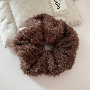 Gros plan d'un chouchou en peluche marron duveteux en fausse fourrure douce sur textile beige