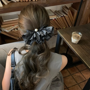 Elegant grey polka dot bow hair clip with pearl center on model with low ponytail