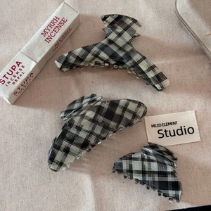 Detail of vintage black and white checkered acetate hair claw clips on beige linen background