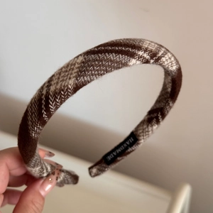 Detail of handmade plaid fabric headband with brown checked pattern and woven label