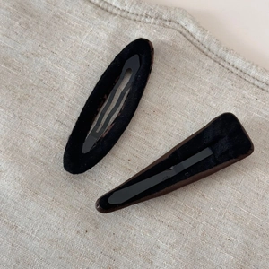 Détail de deux pinces à cheveux en velours noir sur un fond en tissu de lin