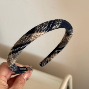 Detailed macro view of retro plaid fabric headband featuring a handmade woven label