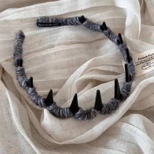 Detail of grey wool-wrapped headband with decorative black spikes and handmade label