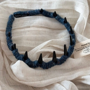 Detail of punk style headband wrapped in blue wool with sharp black decorative spikes