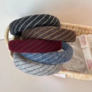 Detail view of five colors of thick ribbed knit headbands with textured twill fabric