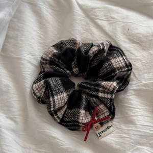Detail of plaid fabric hair scrunchie with red bow, wooden button and happiness label
