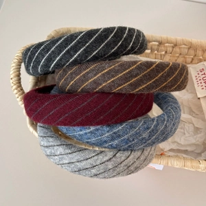Detailed texture of five knitted headbands in grey, brown, wine red, and indigo colors