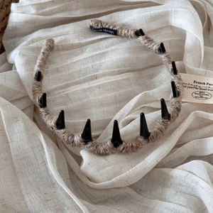 Detail of wool-wrapped headband with black punk spikes and handmade brand woven label