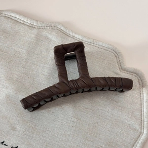 Détail d'une grande pince à cheveux en cuir marron avec texture plissée élégante