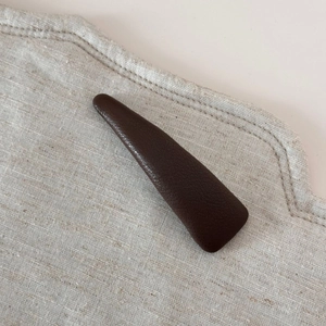 Gros plan sur une pince à cheveux triangulaire marron foncé à texture cuir grainé
