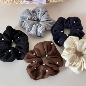 Flat lay of knit scrunchies with pearls in gray, black, navy, brown, and cream tones