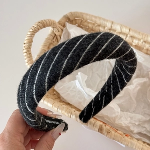 Close-up of thick black twill knitted headband with handmade label and soft texture